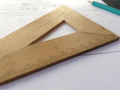 A wooden set square and ruler on a white paper.